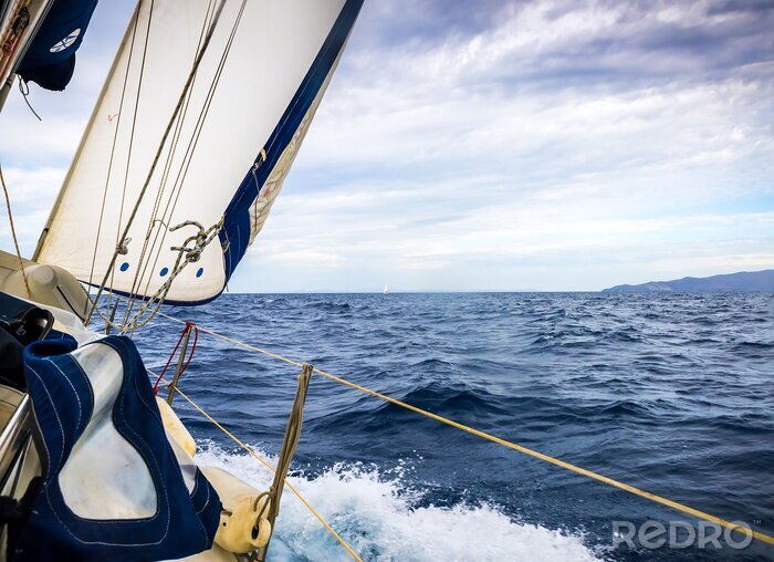 Fotobehang Zeilboot op blauwe golven