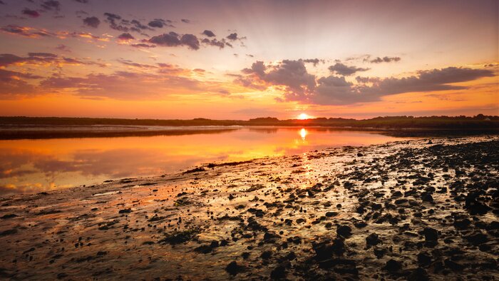 Fotobehang Zonsopgang boven een rotsachtig strand