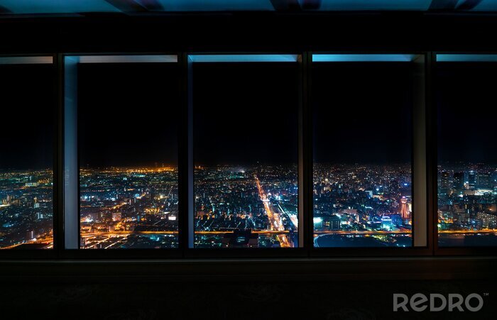 Poster Aerial view of the Osaka skyline at night through a skyscraper window