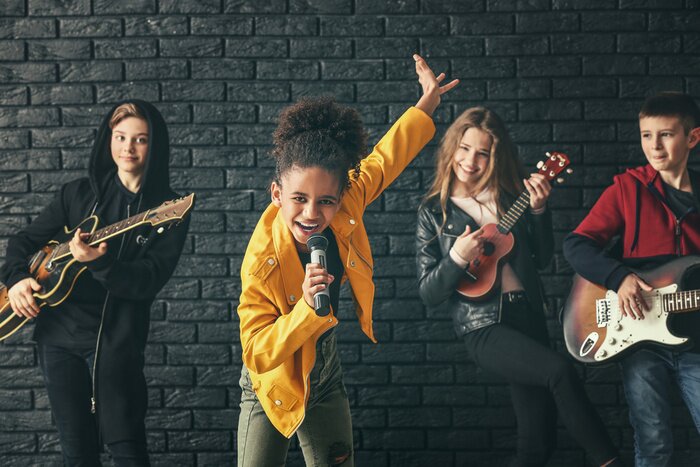 Poster Band of teenage musicians playing against dark wall