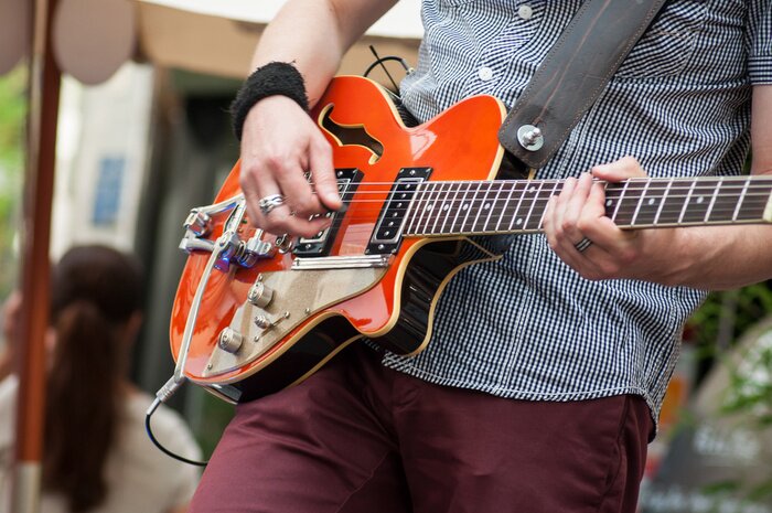 Poster Close-up van gitarist gitaarspelen met rockgroep in de straat