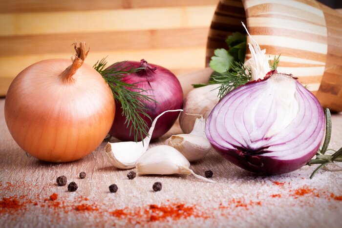 Poster close up van knoflook, ui verse kruiden op een houten bord