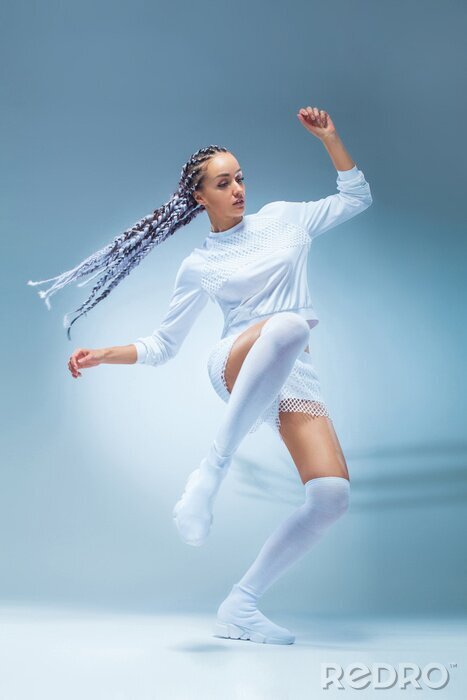 Poster De aantrekkelijke opgewekte danser van het geschiktheidsmeisje in sportwear dans die over blauwe achtergrond wordt geïsoleerd. Mode- en livestyle-concept.