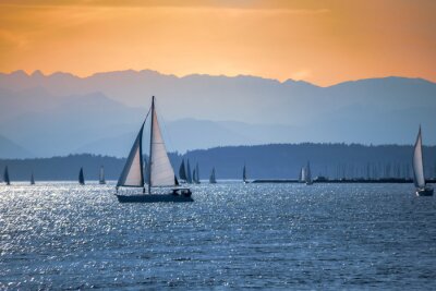 Distant sailboats on the Salish sea with Olympic Mountains at sunset.