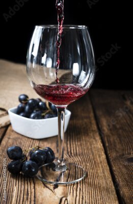 Poster Een glas rode wijn op een houten tafel.