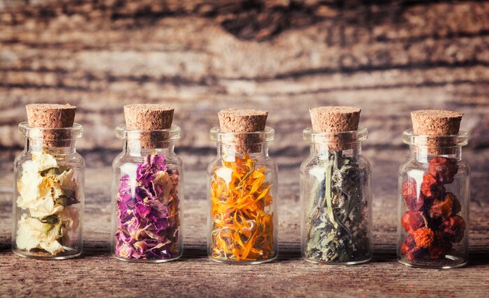 Poster Glazen flesjes met kruiden op een ruwe houten achtergrond