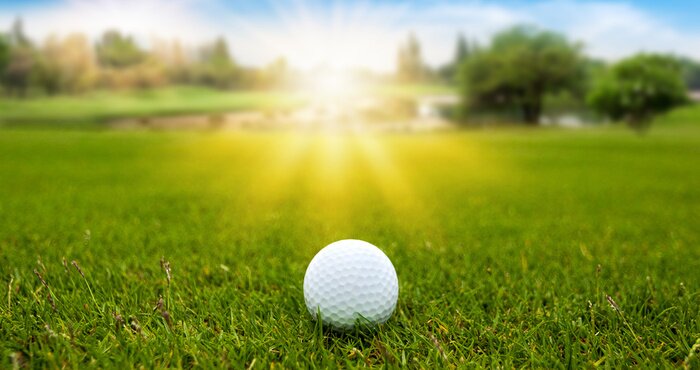 Poster Golf ball on green grass on blurred beautiful landscape of golf course with sunrise,sunset time on background. 