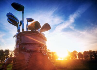 Golftoestel, clubs bij zonsondergang op golfbaan