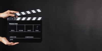 Poster Hand is holding Black clap board or movie slate  use in video production , movie ,film, cinema industry on black background.It have write in number.