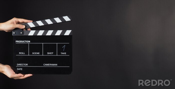 Poster Hand is holding Black clap board or movie slate  use in video production , movie ,film, cinema industry on black background.It have write in number.