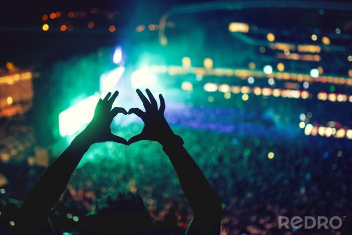 Poster Hartvormige handen op het concert, de liefde voor de kunstenaar en het festival. Muziek concert met lichten en silhouet van een man genieten van het concert