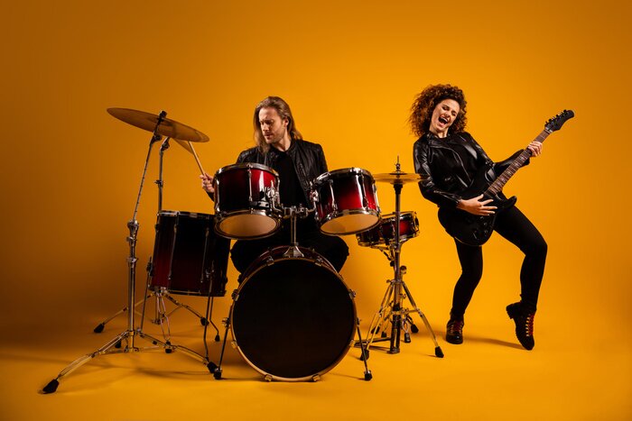 Poster His he her she nice attractive cheerful cheery glad positive couple playing live music bass sound cymbal having fun hobby isolated on bright vivid shine vibrant yellow color background