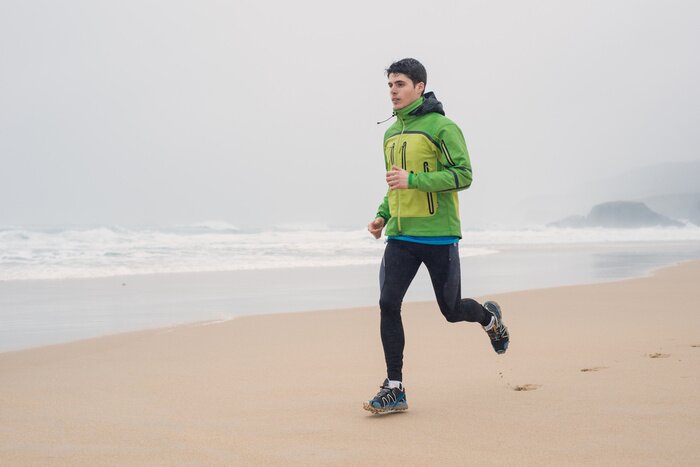 Poster Jonge man lopen op het strand in een regenachtige dag