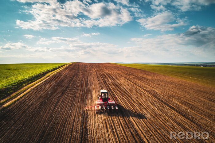 Poster Landbouwer met tractor zaaiende gewassen bij gebied, luchtmening