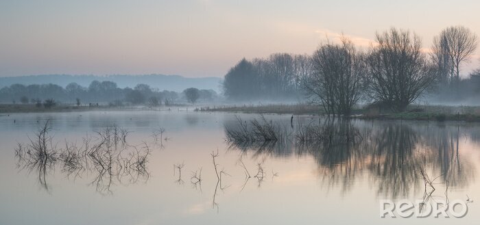 Poster Landscape of lake in mist with sun glow at sunrise