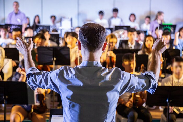 Poster Mannelijke schooldirigent geleidt zijn studentenband om muziek te spelen in een schoolconcert