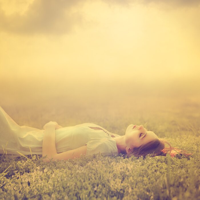 Poster mooi jong meisje droomt van het liggen op een magische weide in het voorjaar