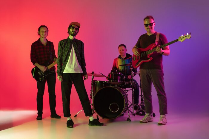 Poster Motion. Young inspired and expressive music band performing on gradient colored background in neon light. Concept of music, hobby, festival, art. Joyful artist, colorful, bright portrait.