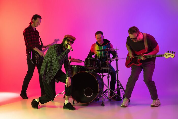 Poster Motion. Young inspired and expressive music band performing on gradient colored background in neon light. Concept of music, hobby, festival, art. Joyful artist, colorful, bright portrait.