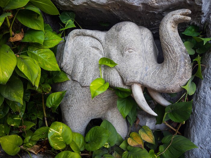 Poster Olifant gemaakt van steen tussen de bladeren