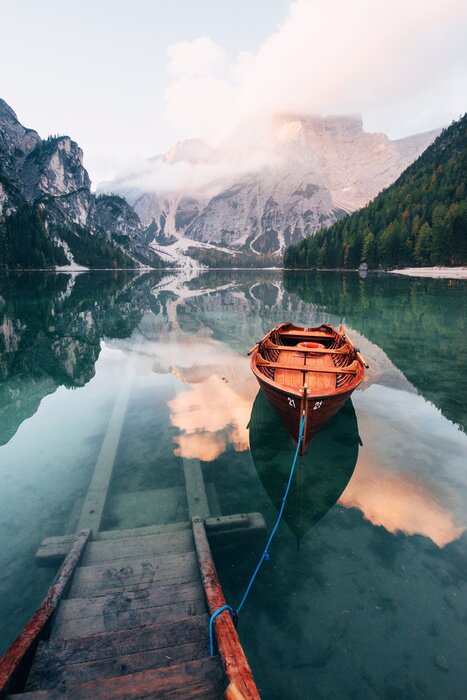 Poster On the pier. Wooden boat on the crystal lake with majestic mountain behind. Reflection in the water