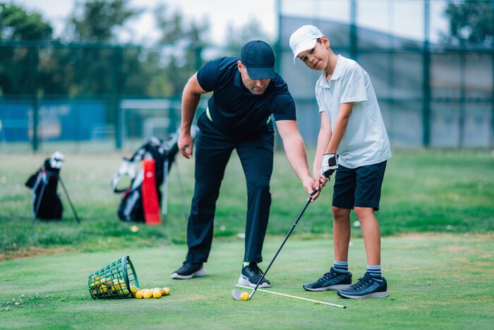 Poster Personal golf lesson. Golf instructor with young boy on a golf driving range.