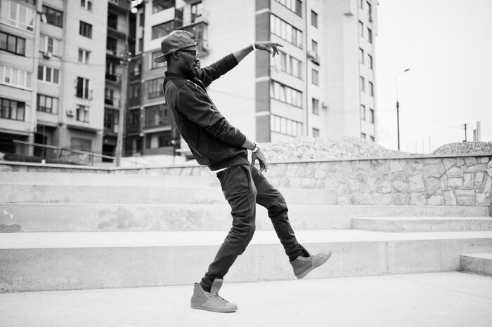 Poster Portret van stijlvolle afro-Amerikaanse man op sportkleding, pet en glazen. Zwarte mannenmodel straatmode, dansende hiphop.