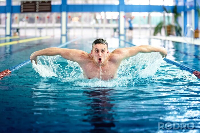 Poster Professionele mannelijke zwemmer, het uitvoeren van de vlinderslag techniek op overdekt zwembad