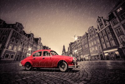 Retro rode auto op geplaveide historische oude stad in de regen. Wroclaw, Polen.