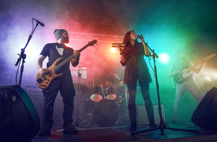 Poster Rock band performs on stage. Guitarist, bass guitar and drums.