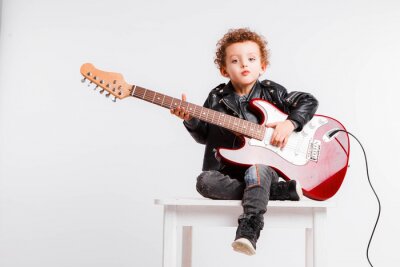Poster Shot of a little curls boy playing rock music with electric guitar.