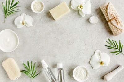 Spa skincare concept. Natural/Organic spa cosmetics products, sea salt and tropic palm leaves on gray marble table from above. Spa background with a space for a text, flat lay, top view.