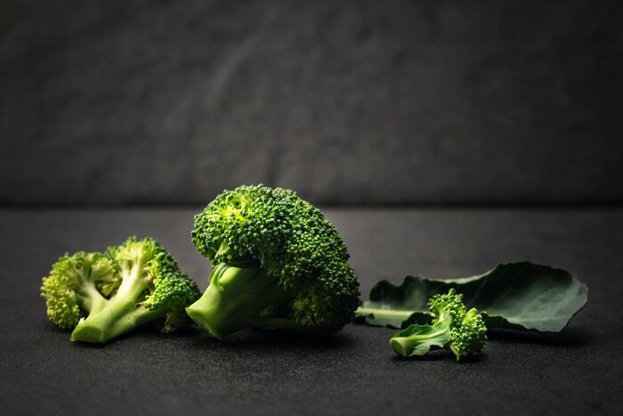 Poster stilleven met verse groene broccoli op zwarte stenen plaat