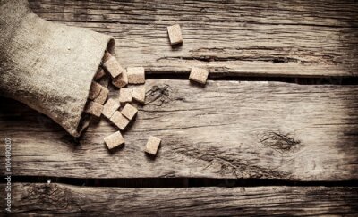 Poster Suikerklontjes van rietsuiker verspreid over houten planken.