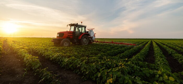Poster Tractor spraying soybean field in sunset