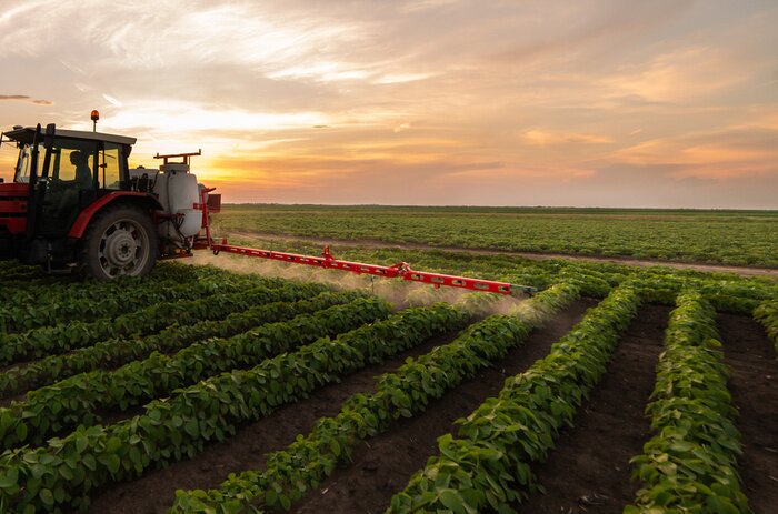 Poster Tractor spraying soybean field in sunset
