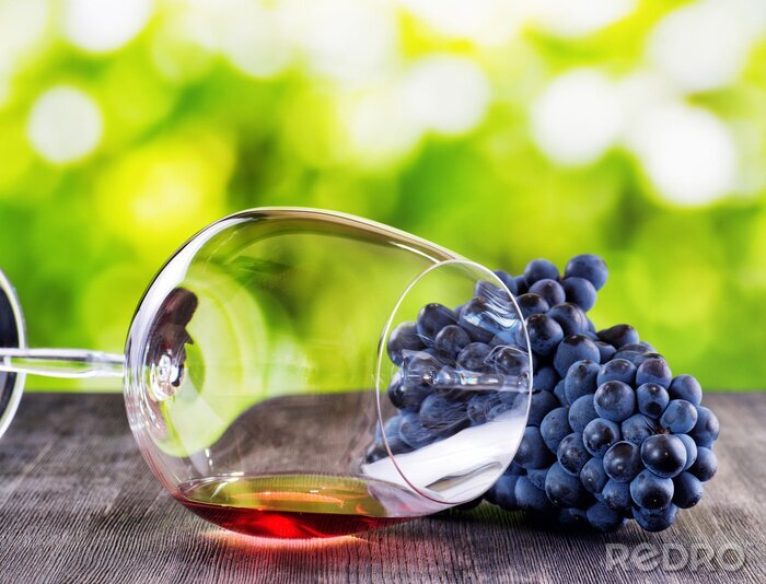 Poster Tros druiven en glas rode wijn die op een zwarte houten ta
