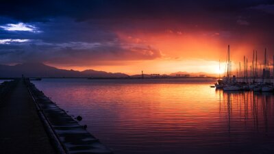 Poster Verbazingwekkende kleuren van de zonsondergang in de haven met een kalme zee
