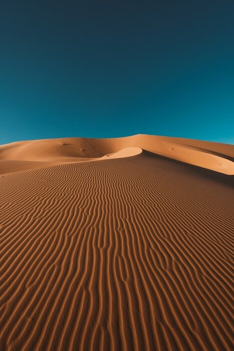 Poster Vertical shot of a peaceful desert under the clear blue sky captured in Morocco