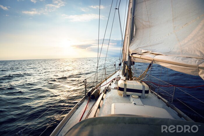 Poster View from the deck to the bow of a sail yacht tilted in a wind on a sunset