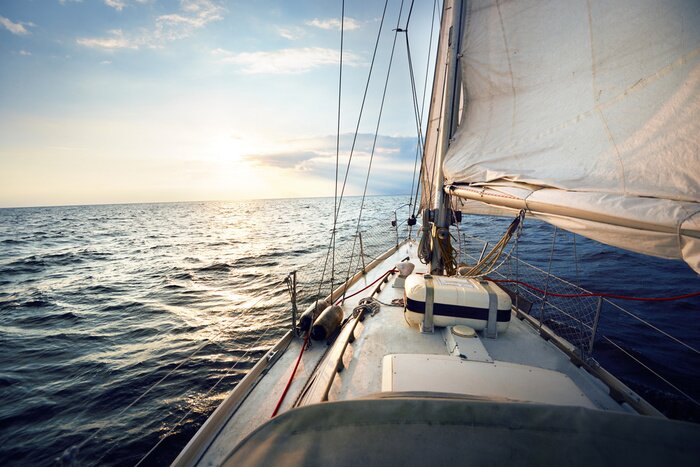 Poster View from the deck to the bow of a sail yacht tilted in a wind on a sunset