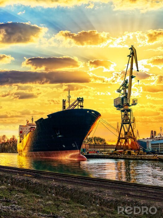 Poster Vrachtschip en de haven bij zonsondergang.