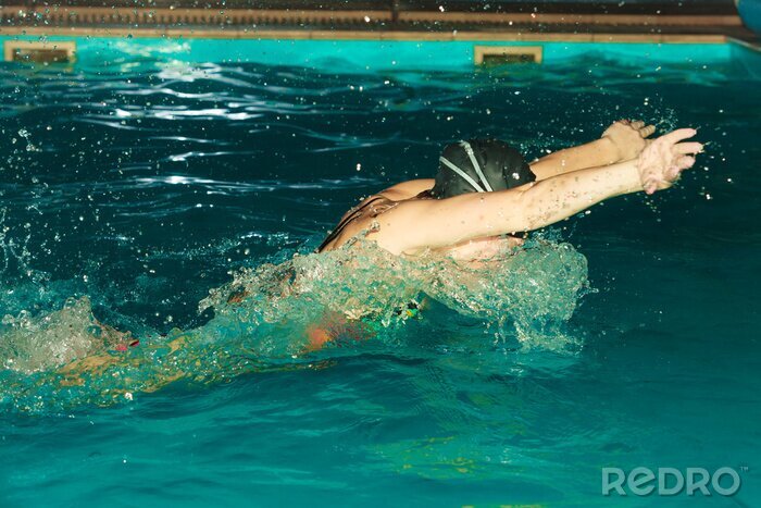 Poster Vrouw atleet zwemmen vlinderslag in het zwembad.