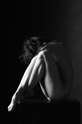Poster Vrouw in een artistieke pose in een donkere kamer