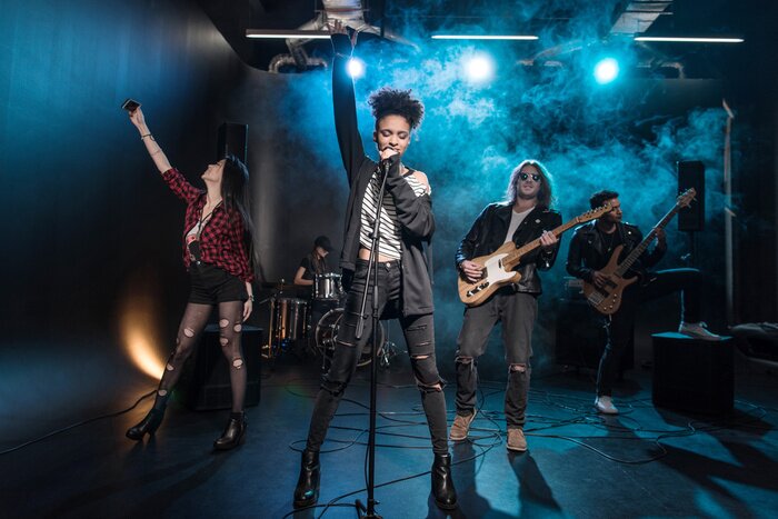 Poster Vrouwelijke zangeres met microfoon en rock-and-roll band die hard rockmuziek uitvoeren op het podium