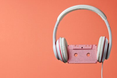 Poster White classic wired headphones with audio cassette isolated on coral color background. Retro style. 80s. Minimalistic music concept.