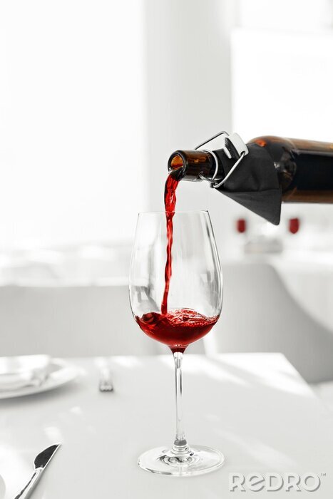 Poster Wijn. Close-up van het gieten van rode wijn uit de fles in glas wijn in een restaurant. Alcoholische dranken. Celebration en levensstijl.