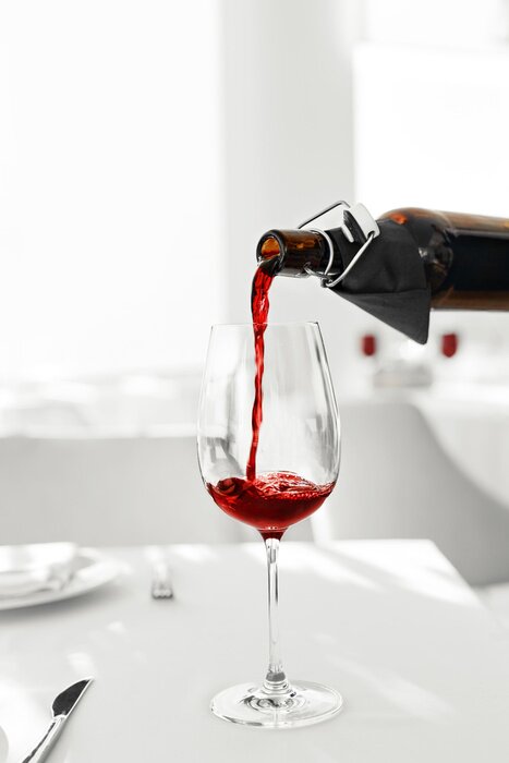 Poster Wijn. Close-up van het gieten van rode wijn uit de fles in glas wijn in een restaurant. Alcoholische dranken. Celebration en levensstijl.