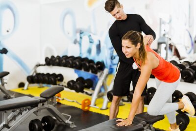 Poster Young male trainer giving instructions to a woman in a gym