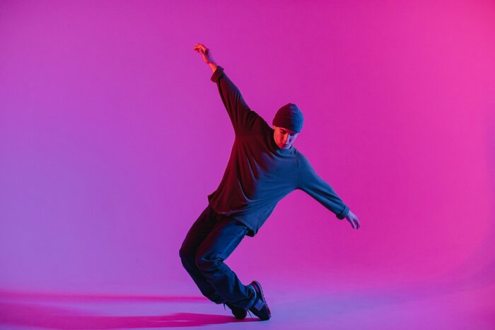 Poster Young Man in a Jumper Dancing Contemporary Dance in Studio. Breakdancing. Dance School Poster. Copy Space. Battle competition announcement. Pink and Blue Background.